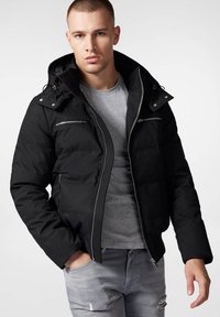 Czarna kurtka puchowa z kapturem, z zamkiem z przodu, czterema kieszeniami na zamek i teksturowanym materiałem. Nosi ją osoba w dopasowanej szarej koszulce.