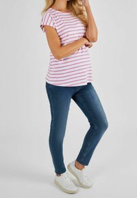 Pruhované růžové a bílé bavlněné tričko s krátkými rukávy, kombinované s modrými skinny džíny a bílými teniskami. Jednoduchý design a přiléhavý střih.