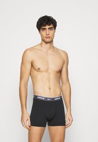 Boxer shorts de algodón negro con una amplia cinturilla elástica que presenta el logo de Nike en blanco. Corte ajustado, textura suave, longitud a mitad del muslo.