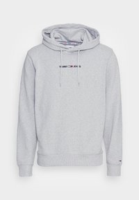 Felpa grigia realizzata in morbido tessuto, con tasca frontale, cordini e logo ricamato "TOMMY JEANS" con accenti di colore.