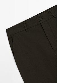 Donkergroene op maat gemaakte broek van stof met een gladde textuur. Kenmerkt zich door een tailleband met elastiek en een enkele knoopsluiting.