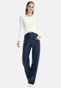 White long-sleeve cropped top with a cross design, paired with navy wide-leg pants featuring side pockets and an elastic waistband.