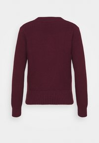 Pull bordeaux avec un motif en maille texturée, encolure ronde et poignets côtelés. Présente un ourlet inférieur ajusté.