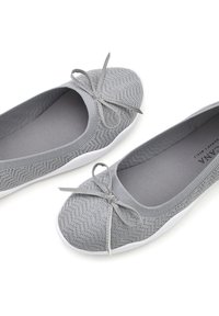 Ballerine grigie in maglia con punta rotonda, un fiocco decorativo sulla parte anteriore e suola bianca. La texture presenta un leggero motivo.