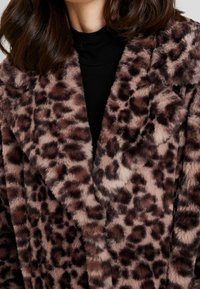 Abrigo de piel sintética con estampado de leopardo y textura suave, con amplias solapas y un diseño cruzado en tonos marrones y beige.