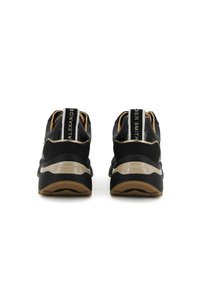 Zwarte sneakers met een zachte stoffen bovenkant, voorzien van een reflecterende hielaccent, een gevoerde middenzool en een gestructureerde rubberen buitenzool.