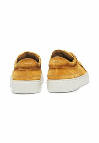 Sneakers in suede giallo con suola in gomma bianca spessa, retro arrotondato e design minimalista caratterizzato da una piccola accentatura sul tallone.