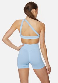 Light blue sports bra with crisscross back design, paired with matching high-waisted shorts. Smooth texture, snug fit, and minimal seams.