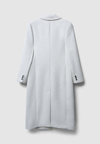 Cappotto grigio chiaro realizzato in tessuto testurizzato, con una silhouette lunga, colletto a pistagna e dettagli con bottoni sulle maniche.