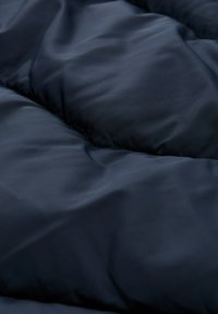 Marineblauer, gestepptes Gewebe mit einer glatten, leicht glänzenden Textur, das gepolsterte Bereiche aufweist, die ein weiches, gepolstertes Erscheinungsbild erzeugen.