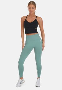 Zwarte sportbeha en lichtblauwe hoge taille legging gemaakt van rekbare stof, met een logo op de legging en een soepele afwerking.