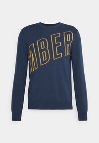 Suéter azul marino de tejido de punto con grandes letras amarillas "MBER" en diagonal por el pecho; cuello redondo y puños acanalados.