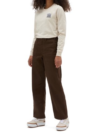 Camicia color crema a maniche lunghe con logo a scacchi, abbinata a pantaloni a gamba larga marrone scuro e sneaker color crema con dettagli marroni.