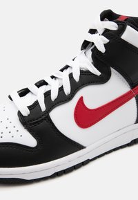 Baskets montantes avec un design en cuir noir et blanc, arborant un logo Swoosh rouge et des lacets blancs. Bout perforé pour la respirabilité.