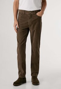 Pantalones de pana marrones con una superficie texturizada, corte recto, bolsillos frontales, cierre de botón y cremallera, y dobladillo a la altura del tobillo.