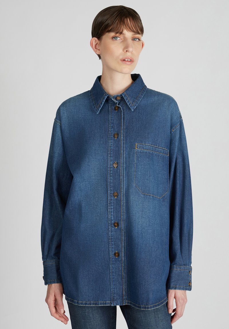Denim overhemd, donkerblauw, lange mouwen, knoopsluiting aan de voorkant, spitse kraag, enkele borstzak, bruine knopen, stikdetails.