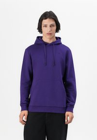 Sudadera morada de tela suave, con un bolsillo canguro, cordones y puños acanalados. Detalle de logo simple en el pecho.