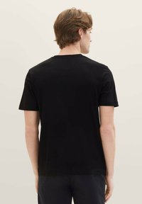 Svart bomulls-t-skjorte med rund hals og korte ermer, med glatt tekstur og vanlig passform. Bildet viser baksiden av skjorten.