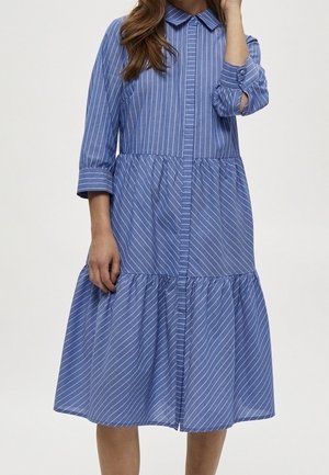 Abito a strisce blu con scollo a camicia, maniche a tre quarti e gonna a strati. Realizzato in tessuto leggero con chiusura frontale a bottoni.