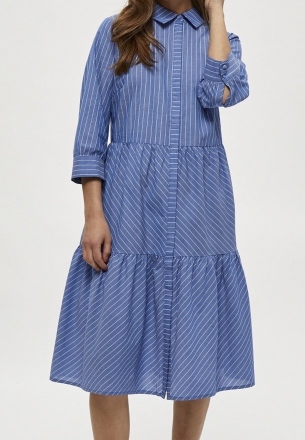 Abito a strisce blu con scollo a camicia, maniche a tre quarti e gonna a strati. Realizzato in tessuto leggero con chiusura frontale a bottoni.