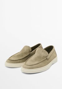 Suede slip-on shoes in light taupe with a rounded shape, tonal stitching, and a white rubber sole for enhanced grip and comfort.