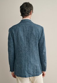 Plavi tweed blejzer s teksturiranim ribljim kostim uzorkom, s reverom i manžetama na tri dugmeta, prikazan sa stražnje strane.