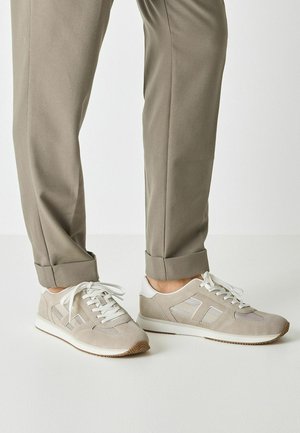 Hellgraue Sneakers aus Wildleder und Mesh-Material, weiße Akzente, runde Spitze und Schnürverschluss; kombiniert mit beigen, strukturierten Hosen.