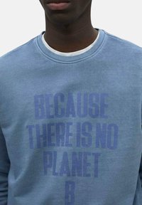 Sudadera azul de algodón. Presenta una gran impresión de texto que dice "PORQUE NO HAY UN PLANETA B" en azul más oscuro. Diseño de cuello redondo.