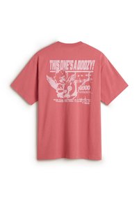 Baumwollt-shirt i koral pink med korte ærmer. Har et grafisk design på ryggen, som inkluderer tekst og en illustration af en figur.