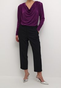 Haut violet à col bénitier avec manches longues, associé à un pantalon noir ajusté et des escarpins argentés à bouts pointus. Tissu lisse avec une coupe décontractée.