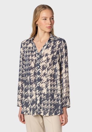 Button-up shirt in navy and cream houndstooth pattern, lightweight fabric, long sleeves, pointed collar, small front pocket detail.