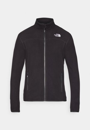 Mustap fleecetakki, jossa on korkea kaulus, edessä vetoketju ja kaksi sivutaskua. Oikeassa yläkulmassa valkoinen logo. Sileä pinta.