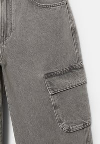Pantaloni cargo in denim grigio con una grande pattina sulla tasca laterale e dettaglio di cuciture visibili su uno sfondo chiaro.