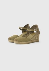 Grønne espadrille-hæle med overdel i lærred, hæl indhyllet i jute, ankelstropper og en struktureret vævet bagside. Rund tå-design.