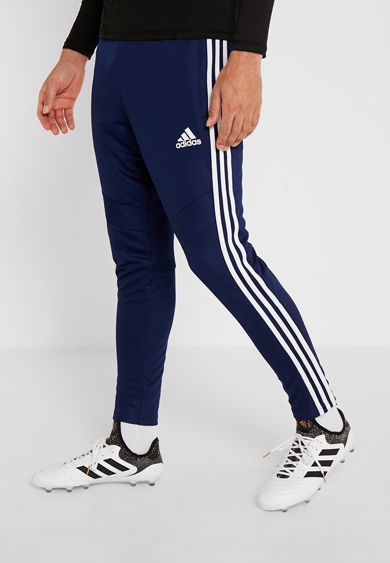 Navy athletic pants with three white vertical stripes, made from smooth fabric, featuring tapered legs and an elastic waistband.