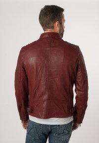 Rote Lederjacke mit strukturiertem Design, Reißverschlussärmeln und verstellbaren Seitenschnallen. Glatte Textur und sichtbare Nähdetails.