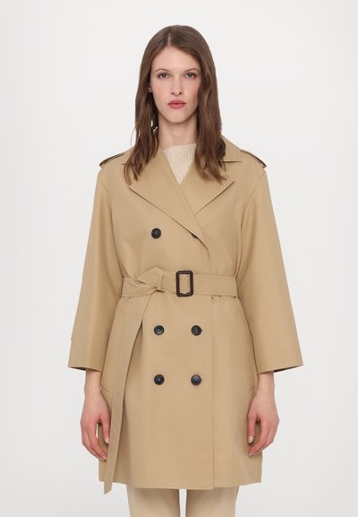 Cappotto trench beige con design doppiopetto, bottoni neri e cintura. Presenta un colletto a rever e maniche a tre quarti.