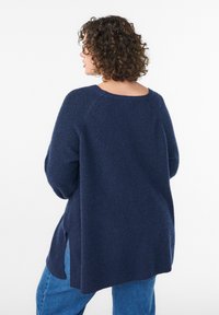 Maglione blu navy lavorato a maglia con vestibilità ampia, scollo rotondo e spacco laterale. Presenta tessuto strutturato e spalle scese.