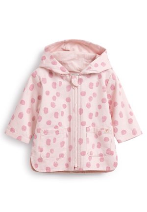 Jasnoróżowa kurtka z kapturem, zapinana na zamek z przodu, z dwoma bocznymi kieszeniami i wzorem w kropki w ciemniejszym różu. Wykonana z miękkiej bawełny.