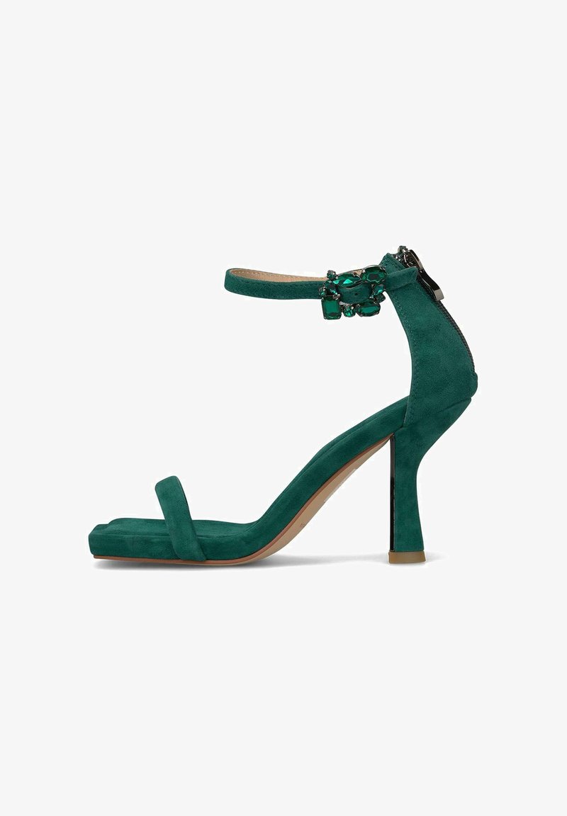 Zielona zamszowa sandał na wysokim obcasie z paskiem wokół kostki, odkrytą palcą i ozdobami. Charakteryzuje się eleganckim wzornictwem i 4-calowym obcasem.