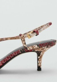 Sandalo con tacco alto in pelle di serpente rossa, beige e nera, con sottile cinturino alla caviglia e fibbia dorata, e tacco a stiletto.