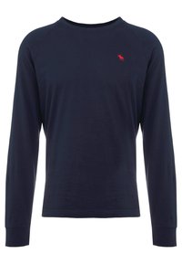 Marineblaues Langarm-T-Shirt aus Baumwolle. Mit Rundhalsausschnitt und einem kleinen roten Emblem auf der linken Brust. Glatte Textur, taillierte Passform.