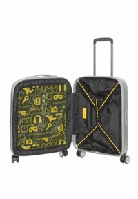 Valigia argento con un interno giallo a motivi che presenta icone di viaggio. L'interno ha una fodera nera e cinghie incrociate elastiche per fissare gli oggetti.