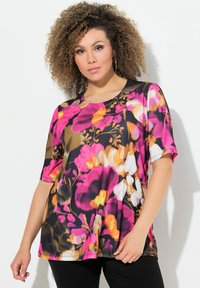 Blusa corta de manga corta con estampado floral que presenta una base negra y vibrantes flores en rosa, naranja y blanco. Textura suave y ajuste relajado con un cuello redondeado.