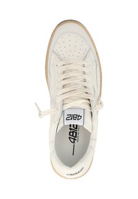 Baskets en cuir blanc avec des perforations, semelle en caoutchouc texturé couleur tan et lacets plats. Présente un logo noir sur la languette et le taquet.