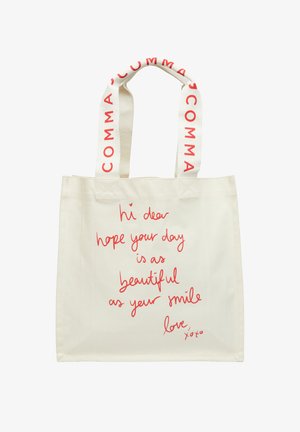 Kremowa torba na ramię z czerwonym, odręcznym napisem życzącym pięknego dnia i uśmiechu oraz kremowe uchwyty z nadrukiem "COMMA" w kolorze czerwonym.