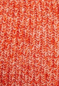 Struktureret strikket stof i nuancer af rød og orange, med en blanding af fluffy, ujævne garn og et chevronmønster.