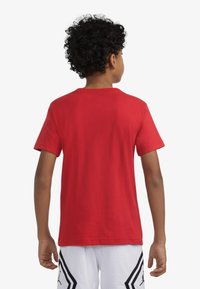 T-shirt rossa in cotone a maniche corte con scollo rotondo. Tessuto liscio, design semplice senza motivi o grafiche visibili.