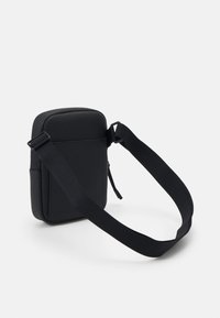 Black crossbody bag featuring a smooth, matte texture, rectangular shape, adjustable strap, and a zippered pocket on the front.