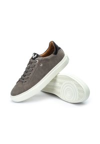 Zapatillas de ante gris con suelas de goma blanca, punta redonda y detalles en cuero negro en el talón. Presentan cordones grises y un logotipo en la lengua.